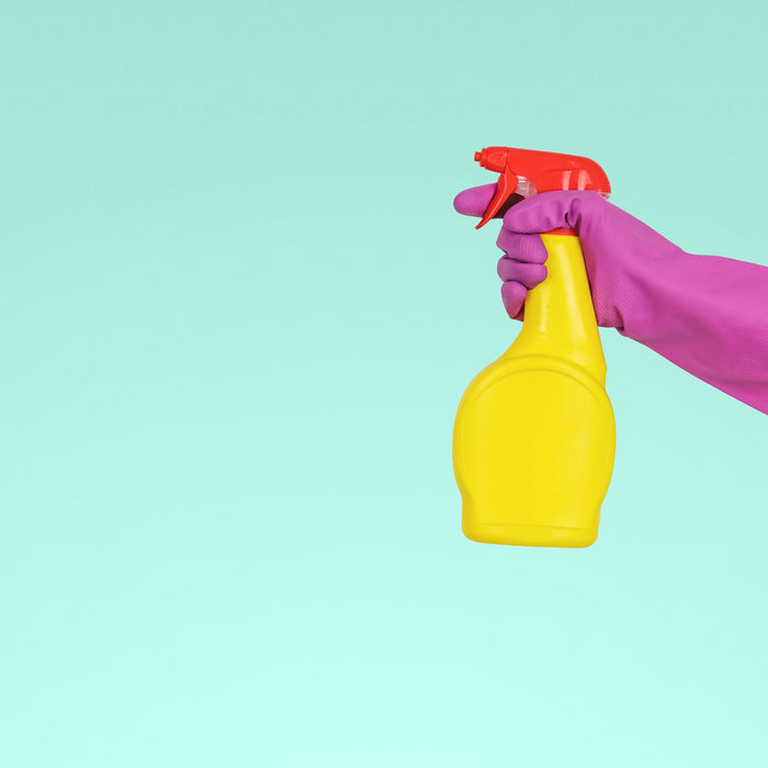  A person in a pink glove holding a yellow color spray bottle