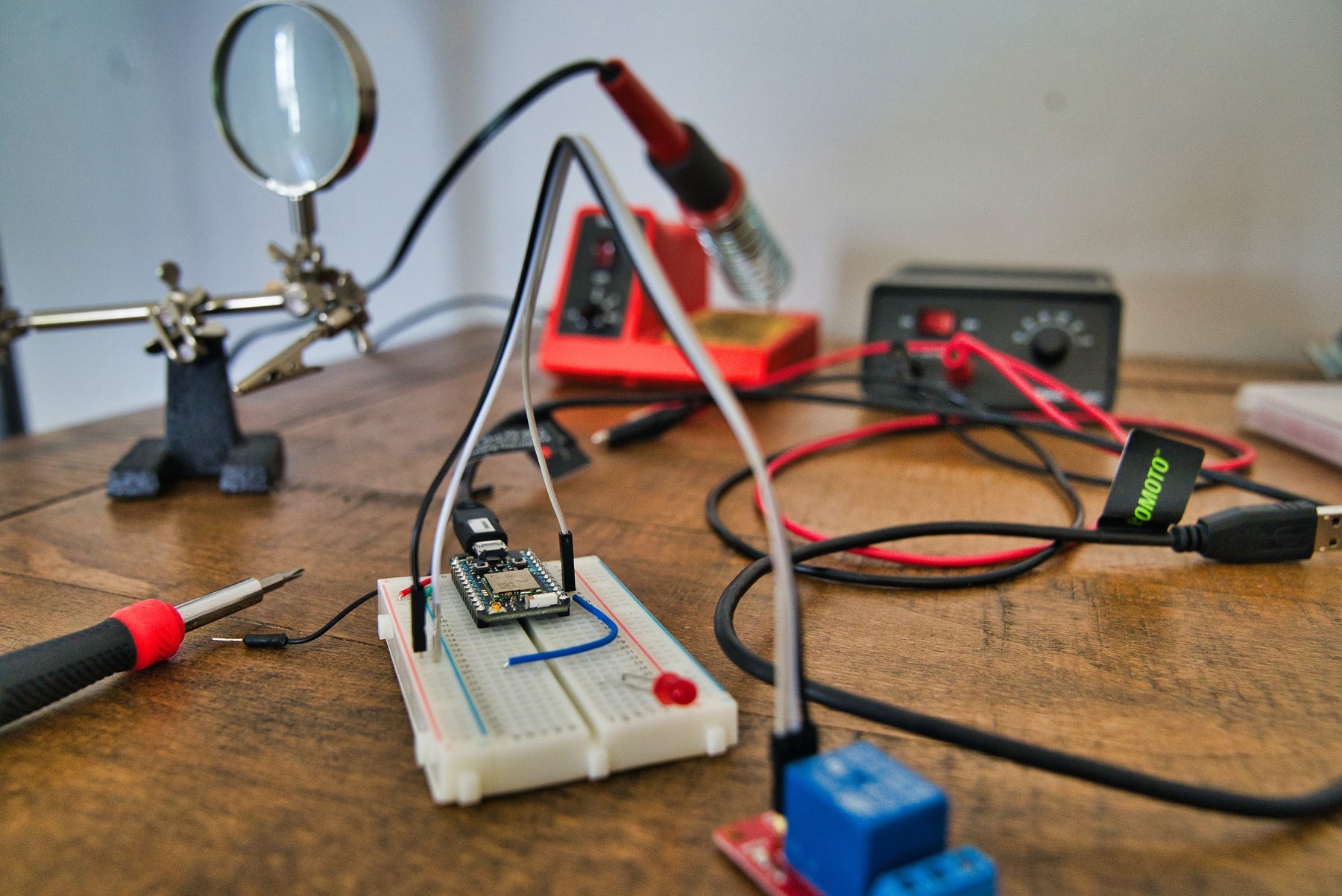 Soldering iron with red handle and other essential electronic equipment arranged on a table