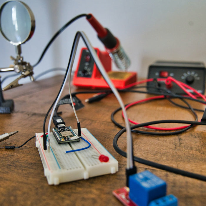 Soldering iron with red handle and other essential electronic equipment arranged on a table