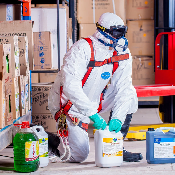 A person wrapped in a white smock and ESD-safe protective equipment handling chemicals