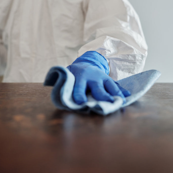 A person in white PPE wiping surface mount contaminants